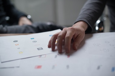 A colour image of a hand resting on a pile of paperwork.