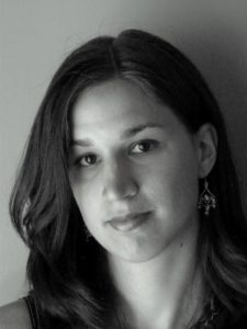 Black and white photo of the author, long hair over one shoulder, slight smile.