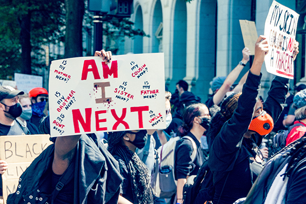 Protestor holding a sign reading "Am I Next"?